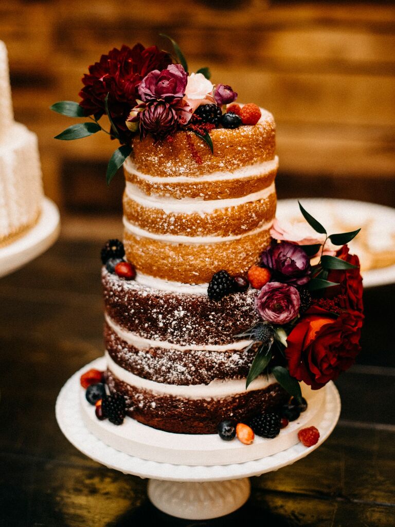 two tier winter naked wedding cake with powdered sugar, fresh berries and burgundy flowers