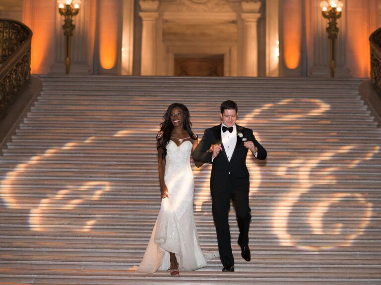 Bride and groom walking down grand staircase. 