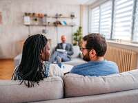 couple sitting side by side on a couch with a therapist opposite them