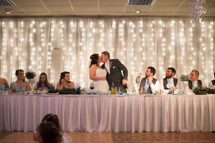 Behind the head table, a curtain of sheer fabric and fairy lights illuminated the space.