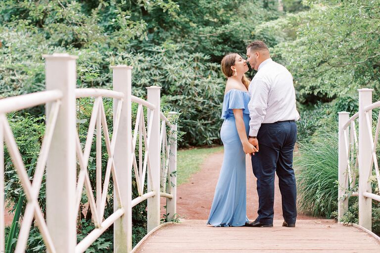 Couple embraces on bridge during garden engagement session