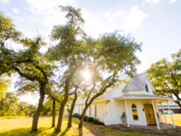 Exterior of small white house in open field at Allegro Wedding & Events Venue in Austin, Texas