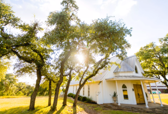 Exterior of small white house in open field at Allegro Wedding & Events Venue in Austin, Texas