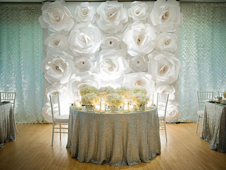 Large white paper flower wall behind a sweetheart table.