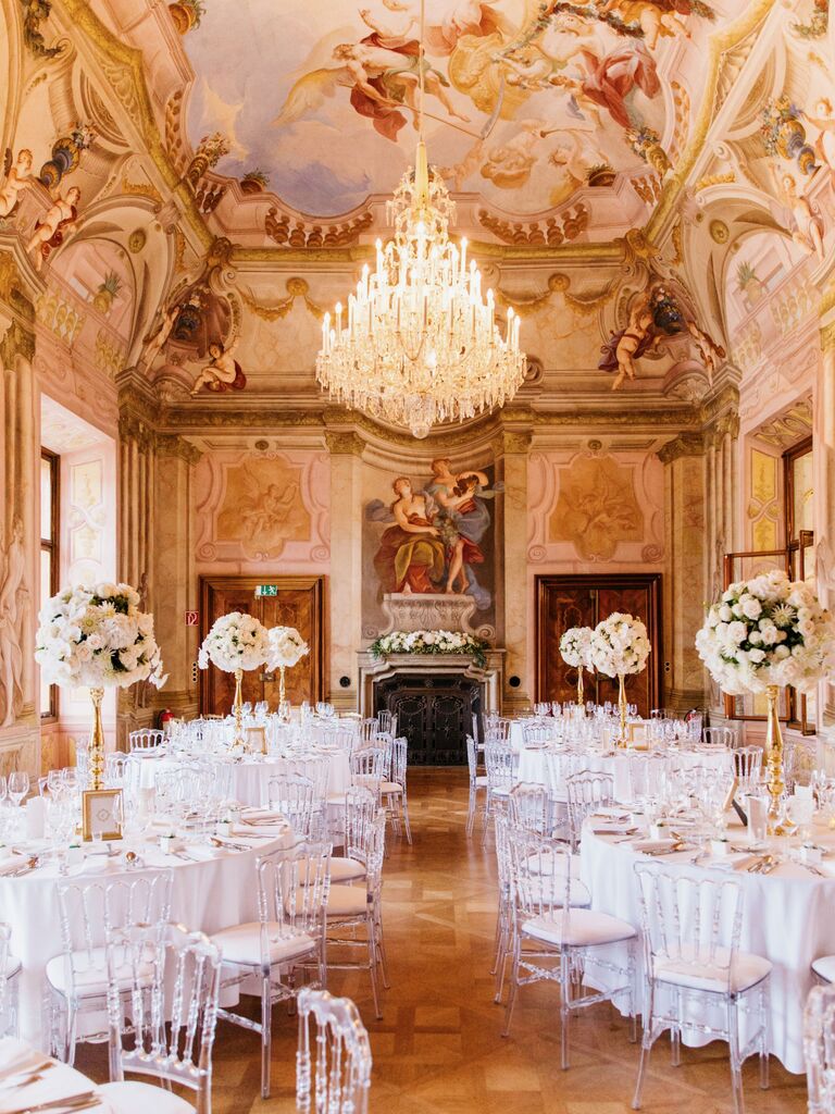 luxury wedding venue historical estate ballroom with painted ceiling, ornate crown molding and crystal chandelier in the center of the room