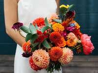Bridal bouquet featuring beautiful dahlias in shades of red, orange, and pink. 