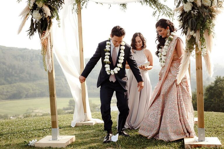 Groom breaking glass during outdoor wedding