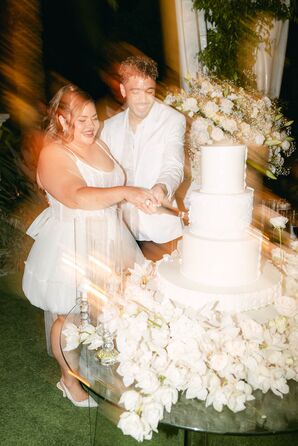 Double-Exposed Photo of Bride in Mini Reception Dress, Groom in White Suit Cutting White Cake