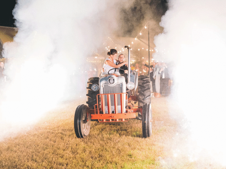 Bride and groom riding a tractor for their wedding exit.