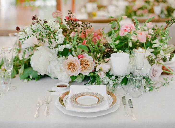 Gold rimmed china and glassware added a luxe touch to the whimsical, tented space. Centerpieces dotted with roses and TK filled the feasting tables.