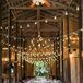 The barn reception featured a long farmhouse dining table that was covered in navy linens, a burlap table runner and blush napkins. String lights hung above the table and the wooden folding chairs. Lauren and Daniel's seats were decorated in a gold "Mr & Mrs" sign.