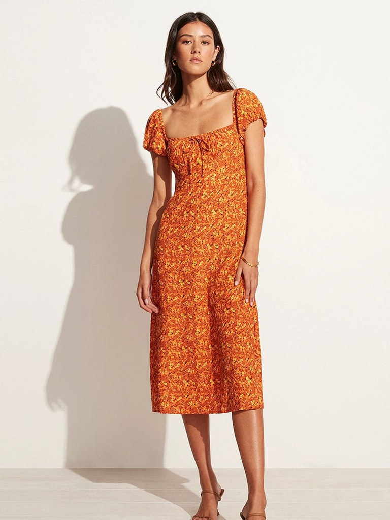 A model wears this cap-sleeve floral wedding guest dress.