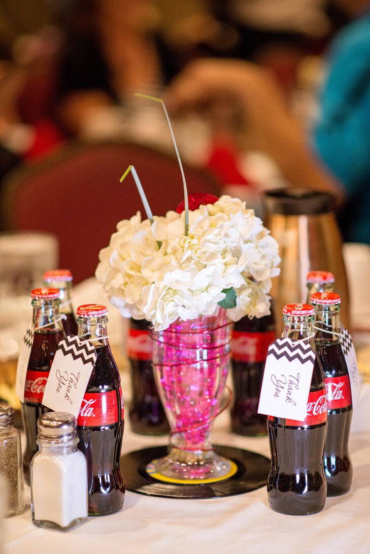 Leah and Cody came up with tremendously creative retro centerpieces with sundae glasses filled with white hydrangeas to look like whipped-cream-topped malted milkshakes. Glass coca-cola bottles doubled as both refreshments and retro-themed place cards.