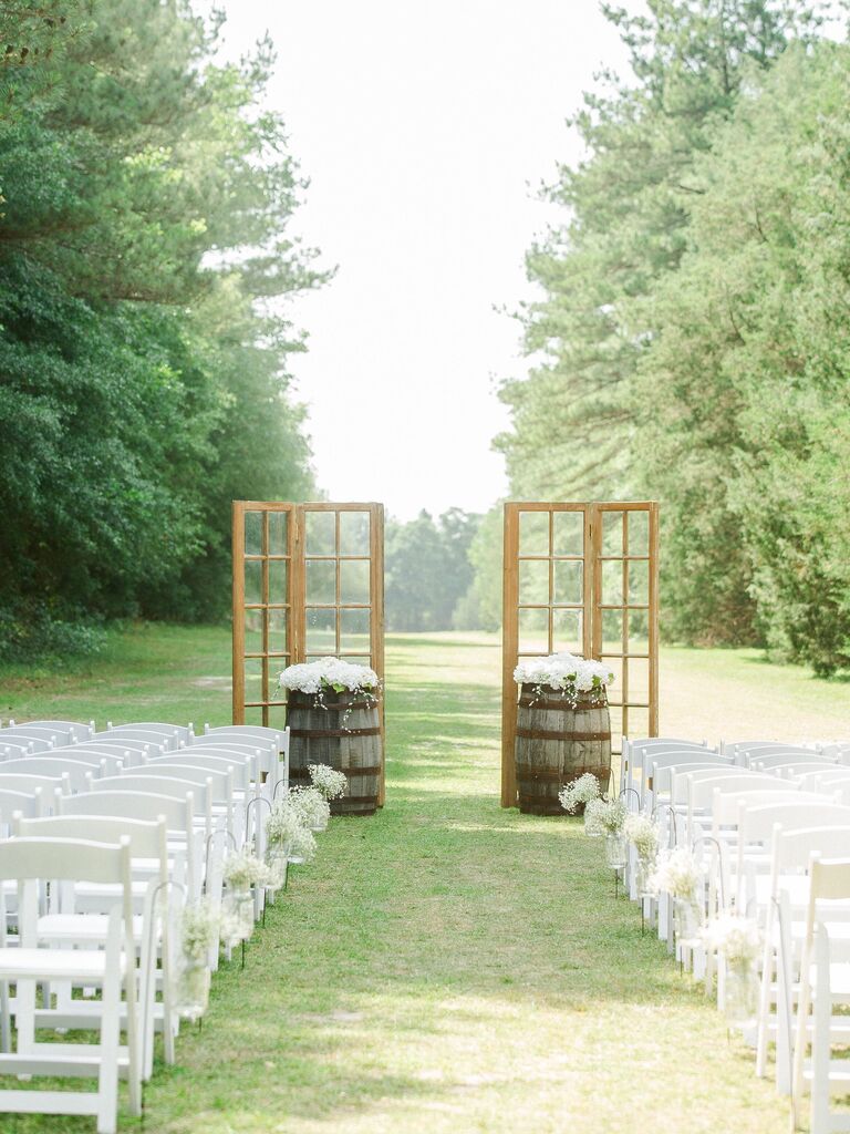 rustic outdoor wedding ceremony decor with wooden window panels and wine barrels at altar