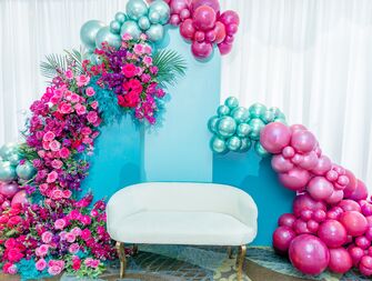 Pink and blue balloon bridal shower backdrop with white couch