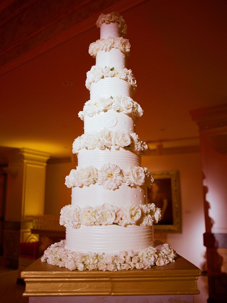 glam seven tier wedding cake decorated with white flowers in between each tier 