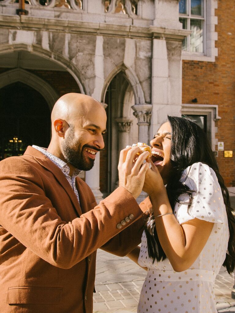 Man feeds his fiance a donut during their engagement shoot. 
