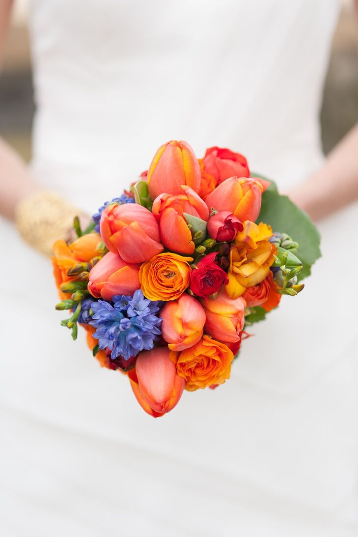 Bright orange tulips and yellow ranunculuses mixed with blue hydrangeas for a colorful bridal bouquet.