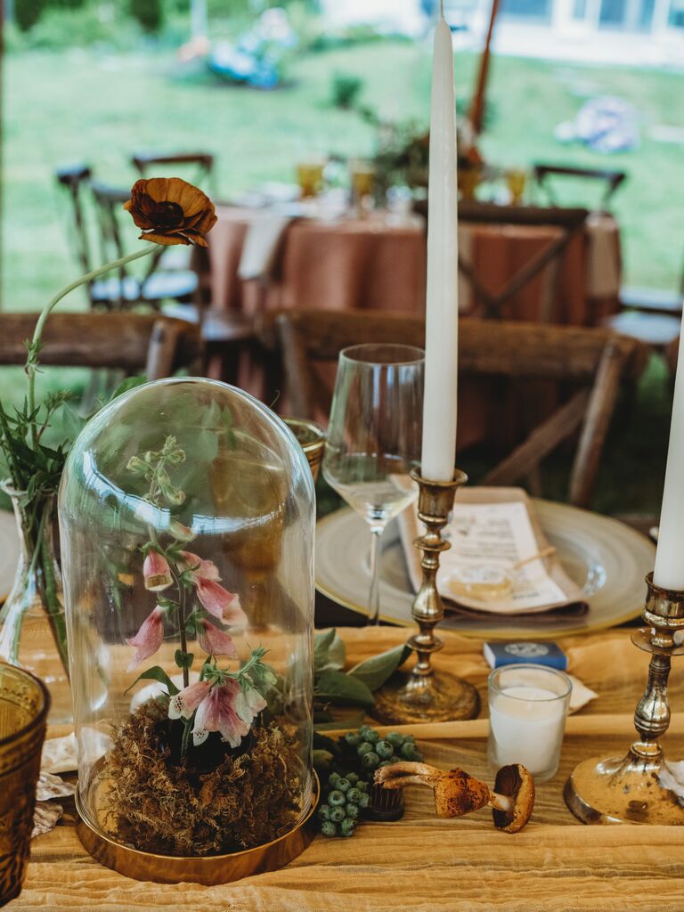 2023 wedding flower trend tablescape with mushrooms, moss and flowers in glass cloche jar