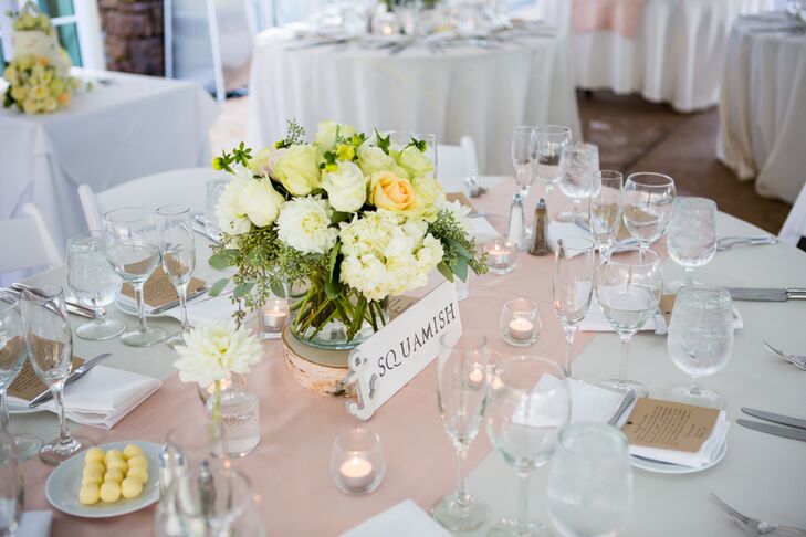 Guests found their seats at dining tables marked with signs, inspired by places along the Hood Canal. White and peach floral centerpieces accented the middle of dining tables, surrounded by votive candles on top of champagne runners.