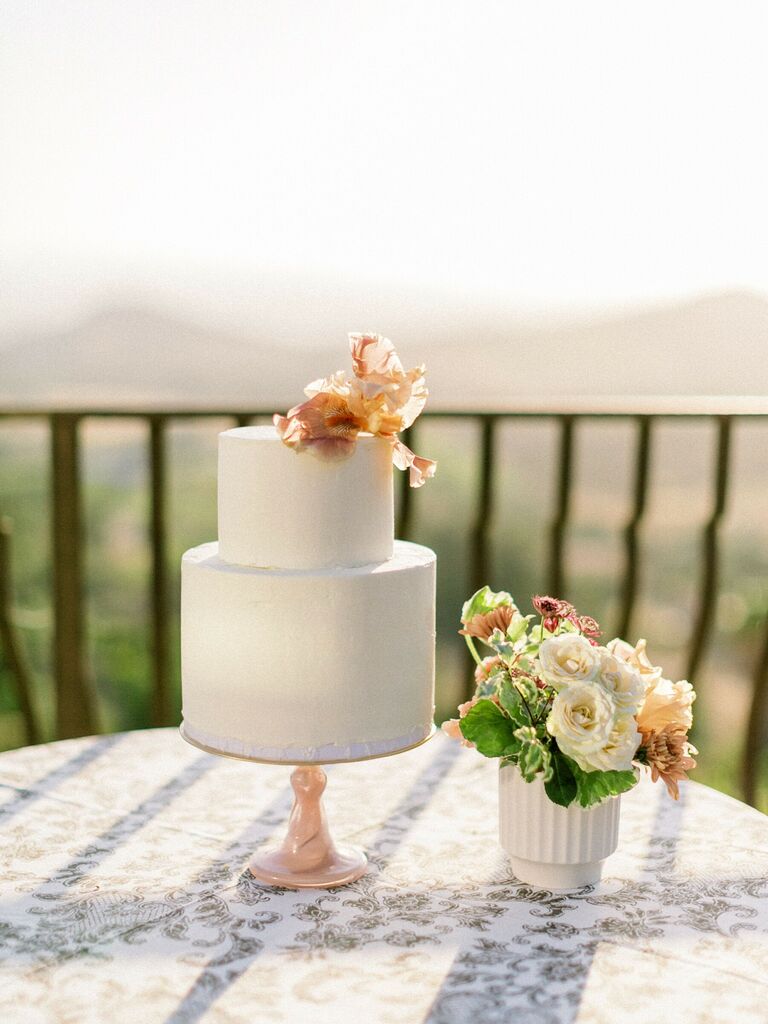 two tier white wedding cake with peach iris on top