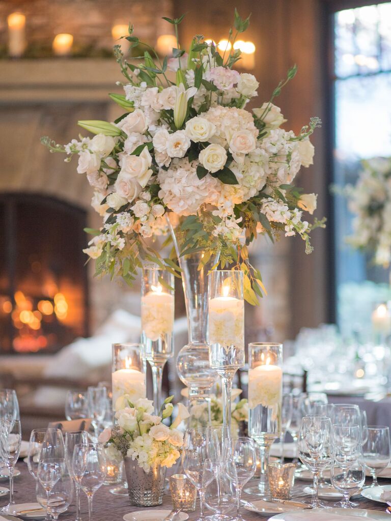 classic tall wedding centerpiece with white flowers in glass vase and floating candles in smaller vases around the table
