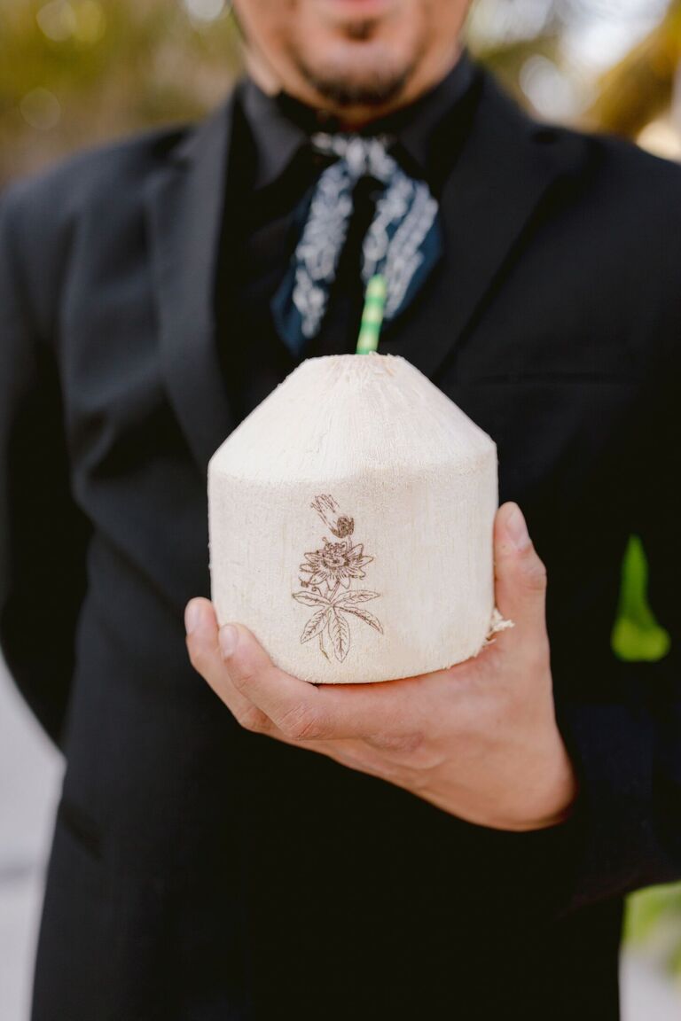 Waiter holding signature cocktail in fresh coconut