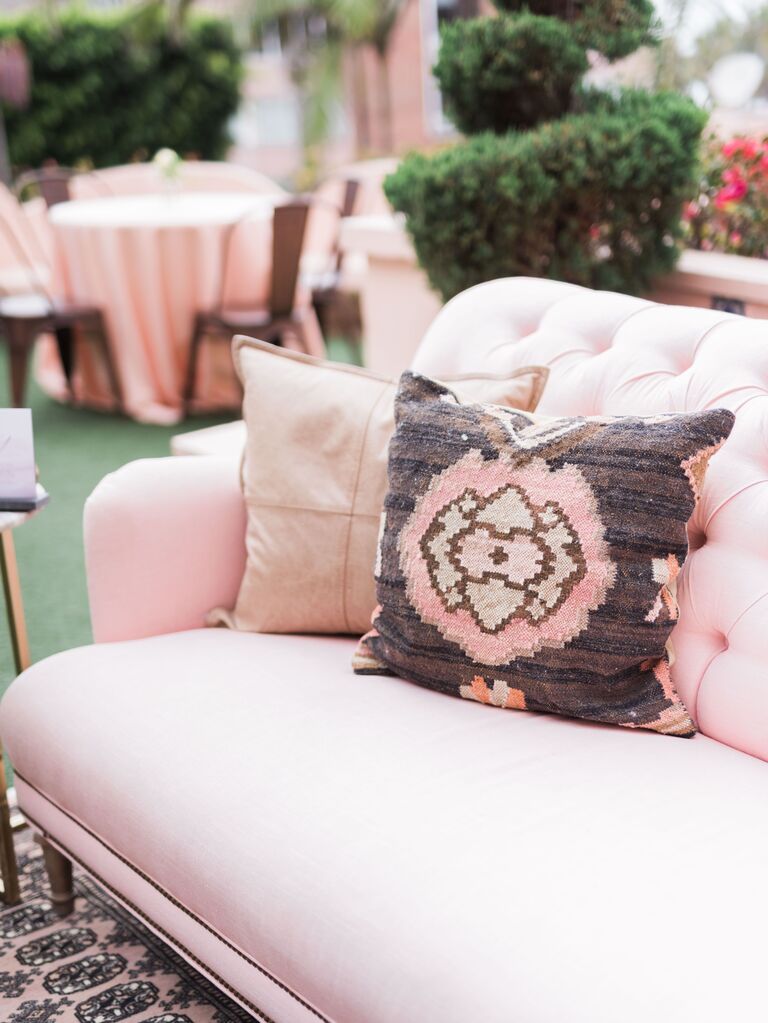 closeup of wedding lounge area with blush pink sofa and pink boho patterned throw pillow