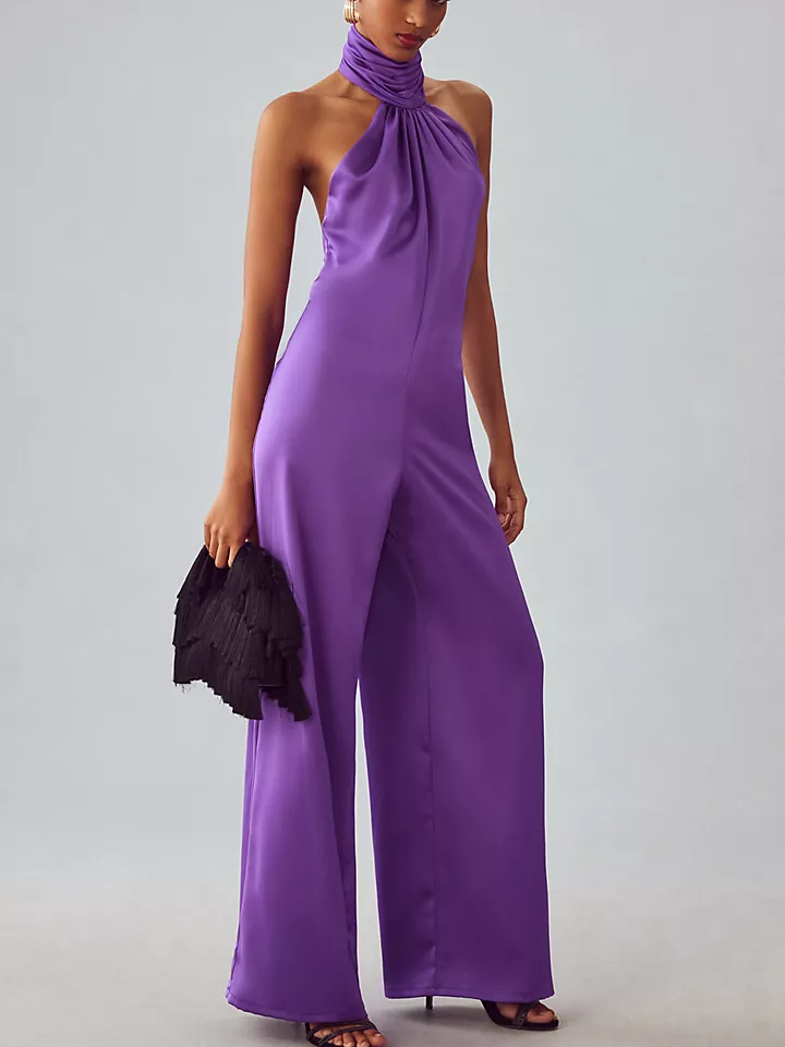 Model wearing a black halter-neck jumpsuit with an open back