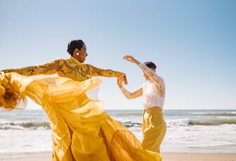 Couple dancing on the beach in coordinating yellow and lace outfits