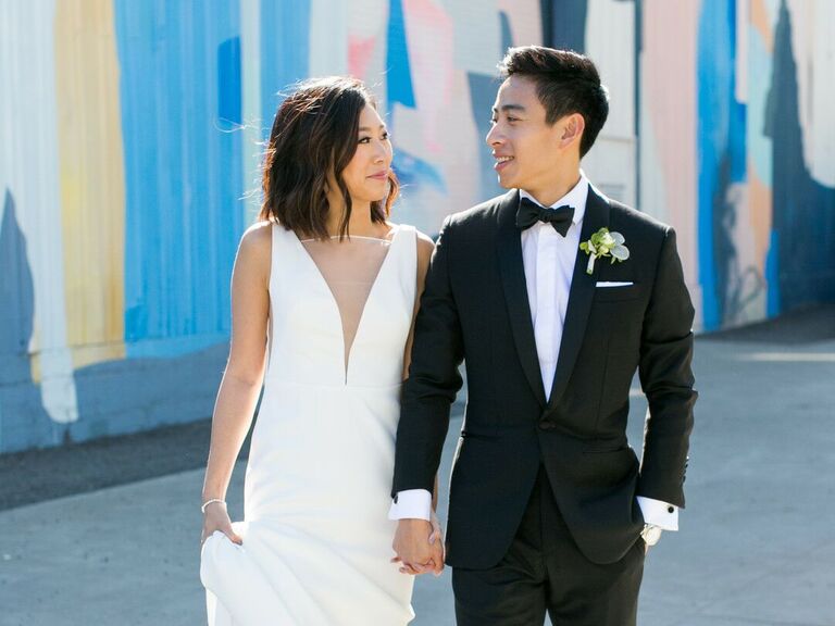 Bride wears her hair in loose textured waves while walking hand-in-hand with her new husband. 