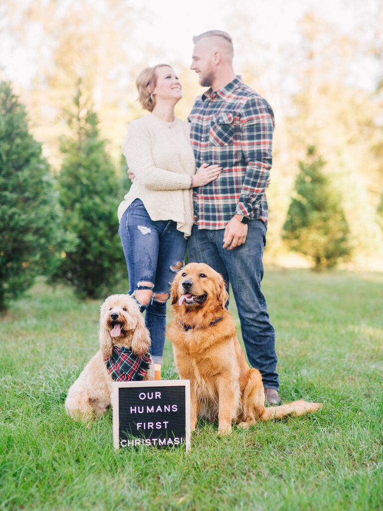 Happy couple smiling while getting their picture taken with their dogs.