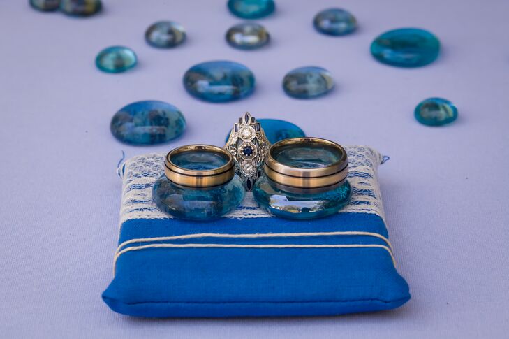 The couple's gold wedding rings that were exchanged at the ceremony were propped up on blue stones supported by the blue-and-white-striped ring pillow. Aly's engagement ring was positioned in the middle, which was silver in a diamond shape accented with a round-cut sapphire in the middle of two round-cut diamonds. The rings were designed by Brilliant Earth.