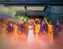 A happy couple and their wedding party set off colorful flares.