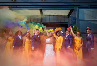 A happy couple and their wedding party set off colorful flares.