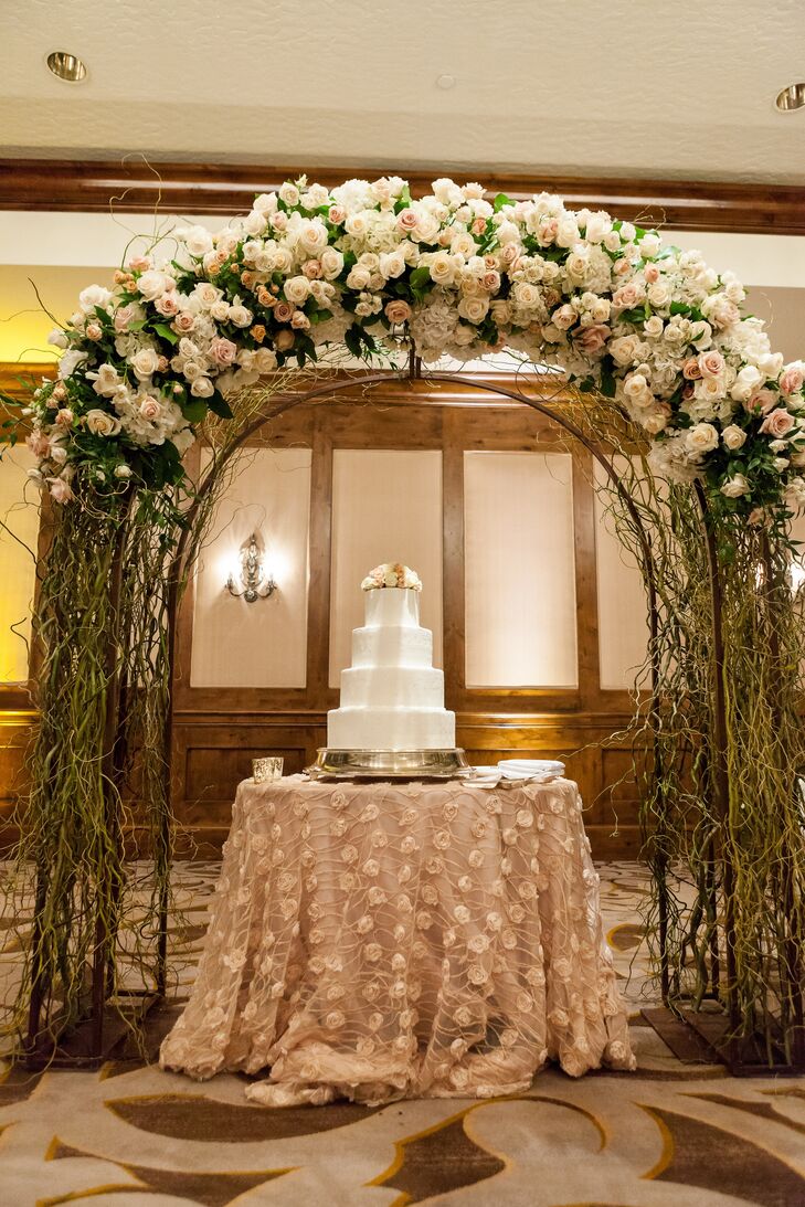 The flavors of the couple's classic, four-tiered wedding cake alternated between carrot (their favorite) and chocolate with fresh raspberry filling. And the cake floral arch above it? Repurposed from the ceremony!