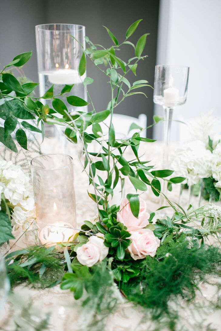 Floating candles—surrounded by lush, leafy greens and blush rose blooms—topped the reception tables and added plenty of romance to the historic,  open space at Historic Riverside Building in Rochester, Minnesota.