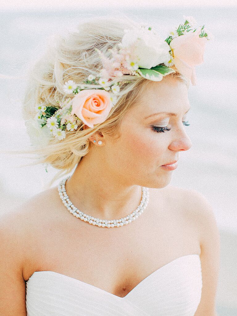 Messy wedding updo with a flower crown made with roses and daises