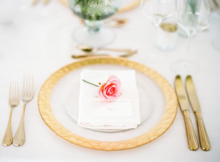 Gold-rimmed dinnerware and brass cutlery radiated in the candlelight, casting a warm, ambient glow over the sleek, modern loft space. A single pink rose was placed on each plate, helping bring the couple’s romantic vision to life.
