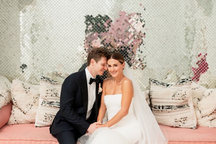 Bride and Groom Pose in Front of Reflective Wall on Pink Couch