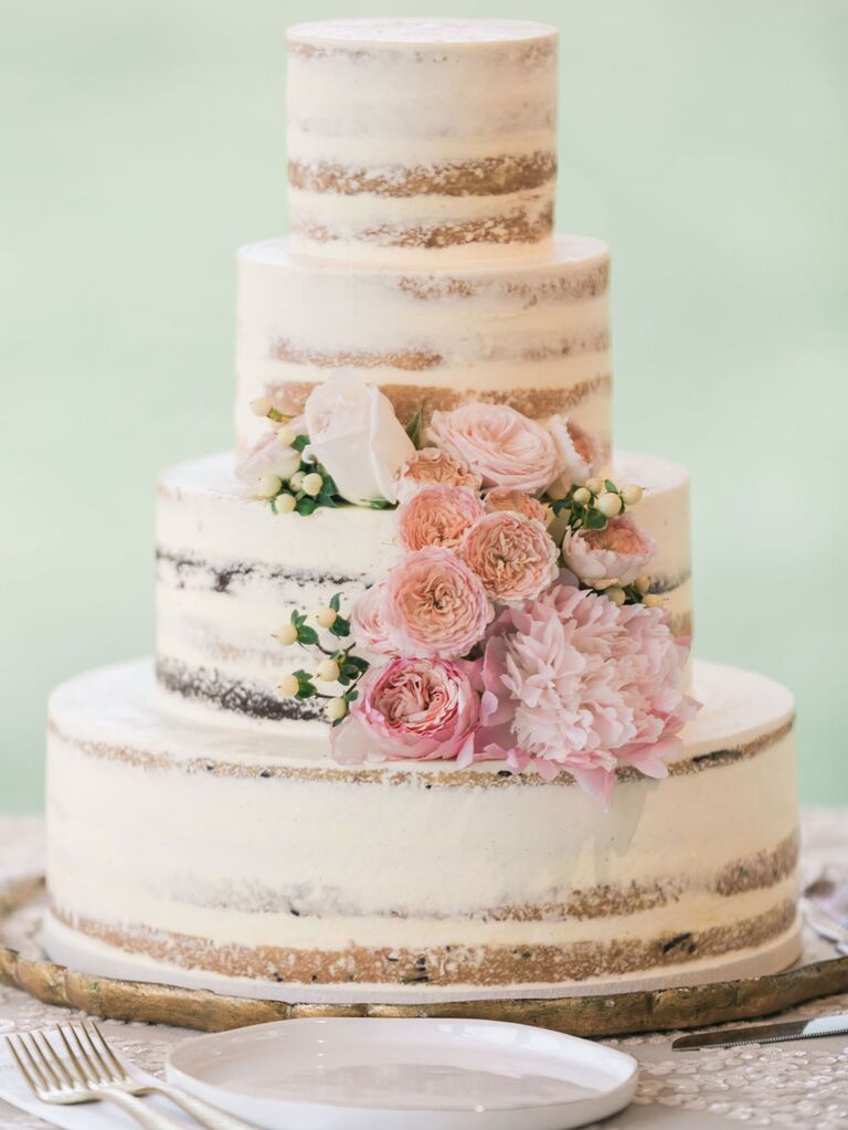 Four-tier rustic wedding cake with semi-naked icing and pink fresh flowers