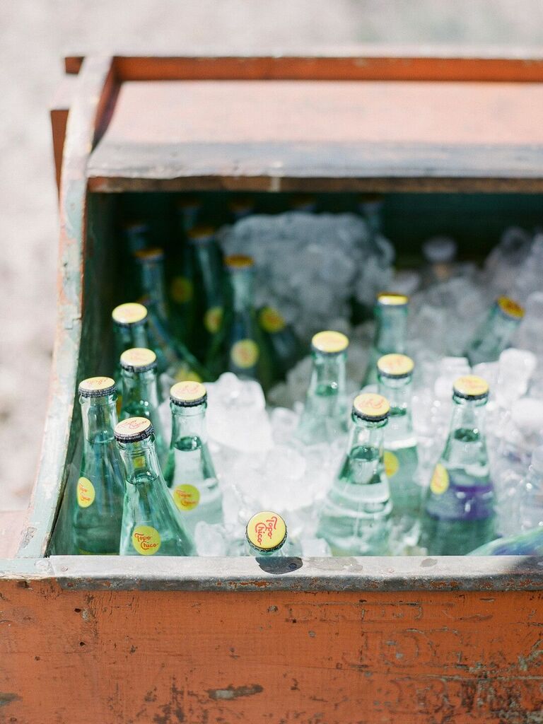 wooden crate with bottles of topo chico water in ice