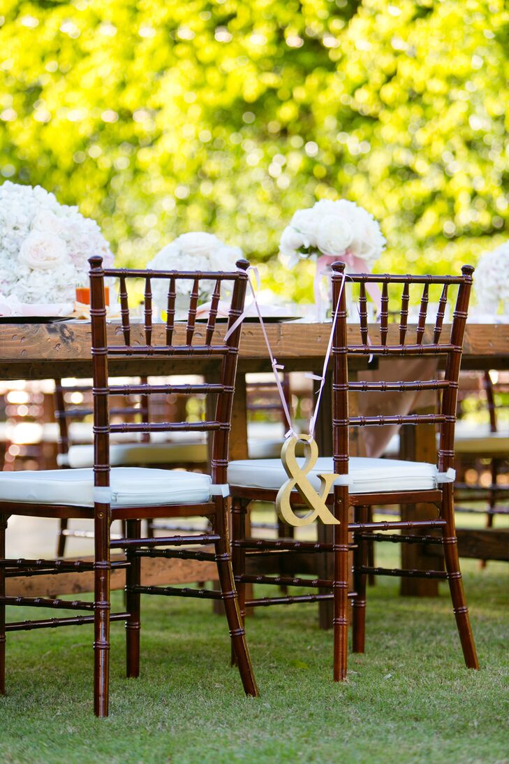 The couple's reception seating stood out with one simple and chic accent. A gold ampersand hung from pink ribbon between their two chiavari chairs.