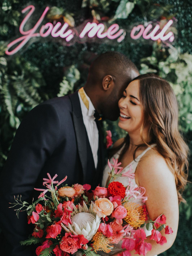 Couple laughing and holding pink bouquet