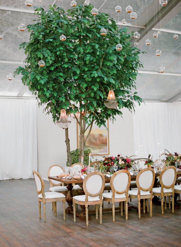 A thousand candles hung from the ceiling and decorated the tented reception along with lush trees, exposed wood tables and whimsical floral centerpieces with feather accents.