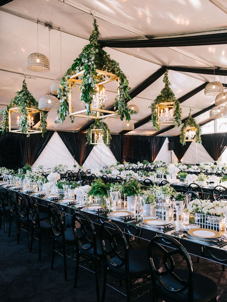 indoor wedding reception with gold square lanterns decorated with greenery