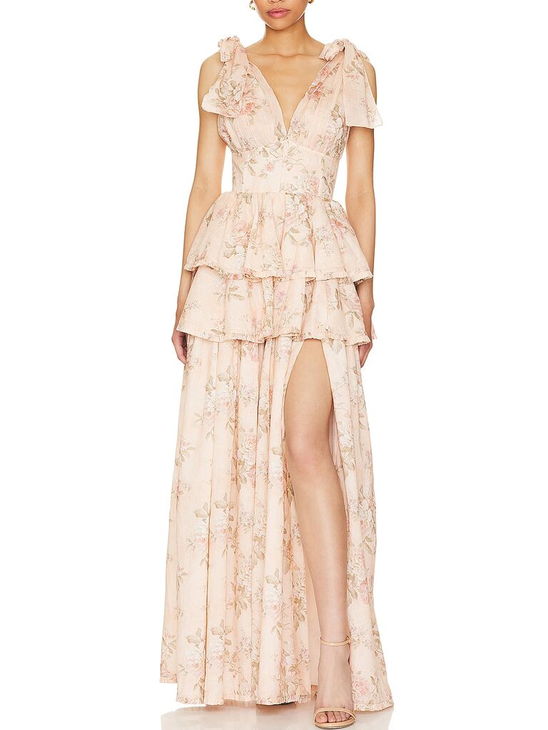 Model wearing a long floral gown with self-tie straps over the shoulder