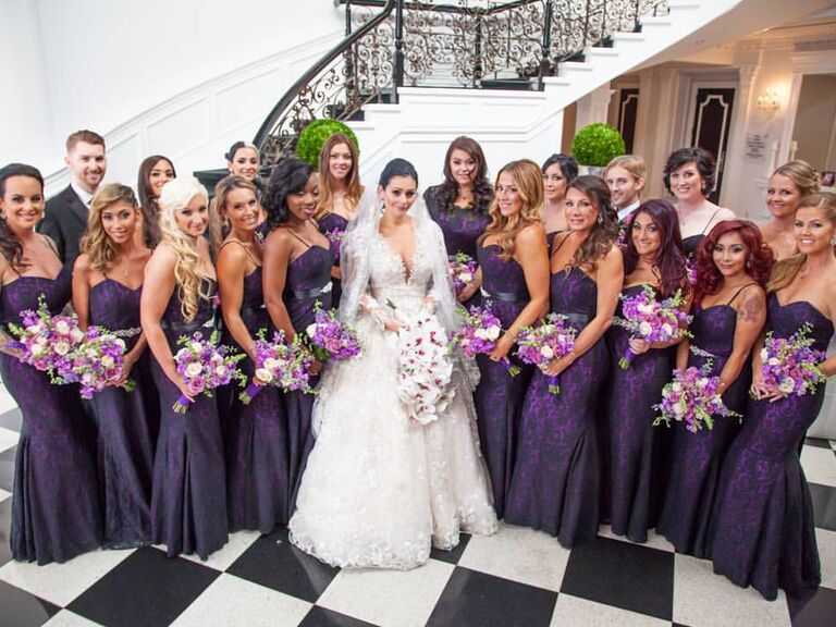 The wedding party wears purple dresses while smiling for the camera. 