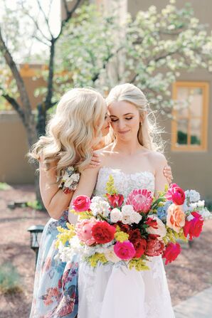 Mother of the Bride in a Floral Gown Embracing the Bride With Colorful Bouquet