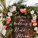 Sunset-hued floral garlands were used throughout the event. Here, one is draped over a wooden welcome sign.